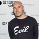 Grant Morrison, in a black sweatshirt labeled "Evil" stands at the Wired Cafe at Comic-Con